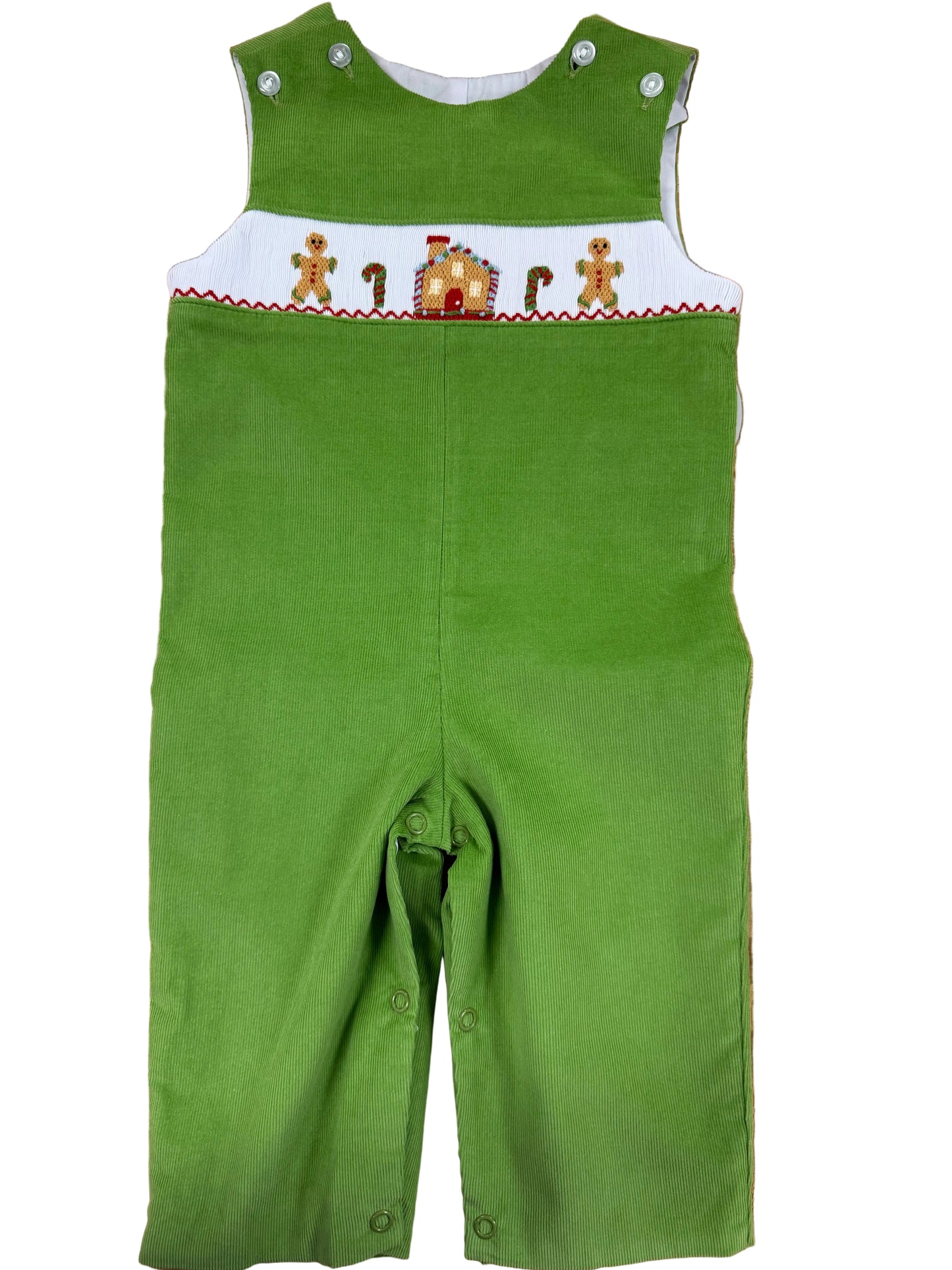 A green corduroy baby overalls romper with a white smocked chest panel featuring gingerbread men and a gingerbread house, laid flat on a wooden floor.