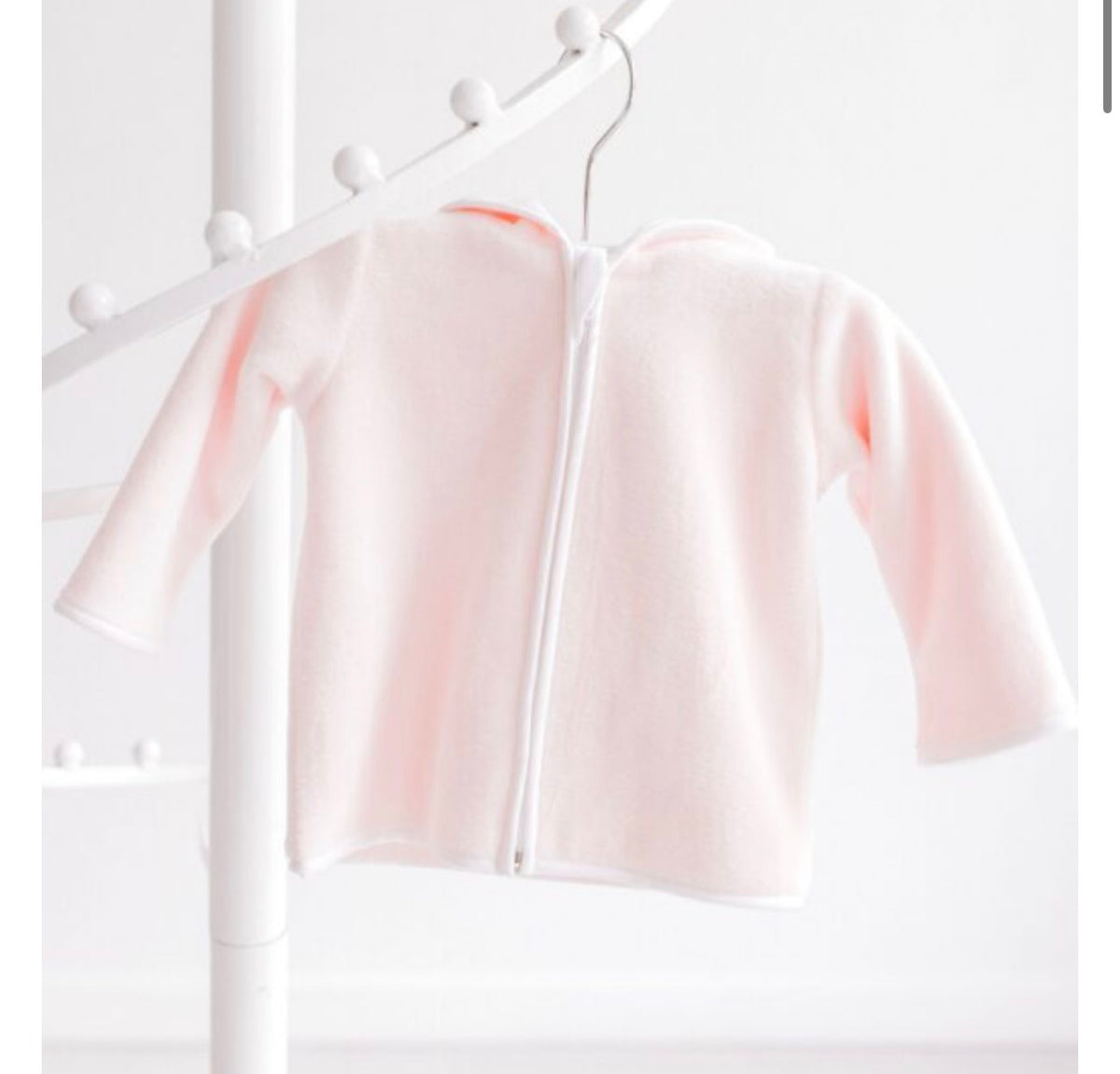 A pale pink hooded zip-up cardigan or sweater displayed on a white clothing rack against a bright white background.