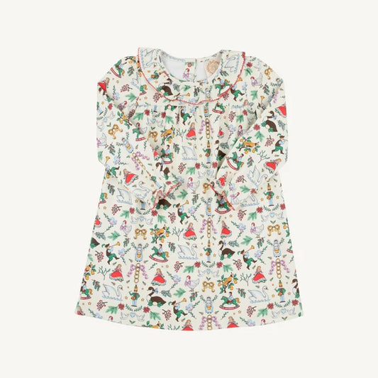 A long-sleeve baby dress with a ruffled neckline and an all-over whimsical print of fairies, elves, and holiday motifs of 12 days of christmas 