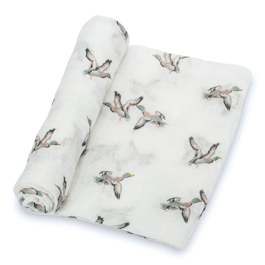 A white muslin baby blanket featuring a printed pattern of flying mallards, shown rolled and flat on a clean white background.