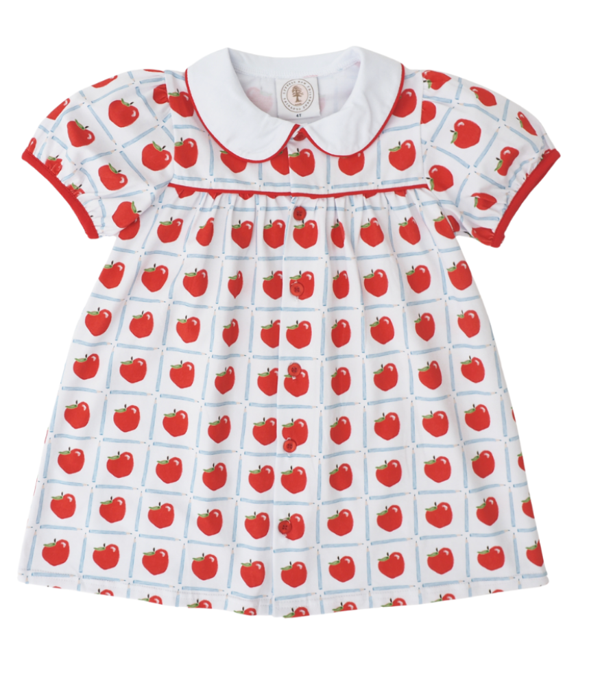 White dress with red apples inside a blue pencil check pattern, with red piping around the collar and short sleeves.