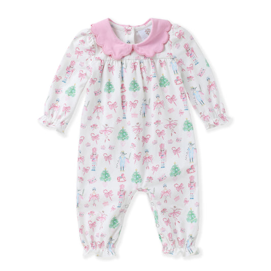 A baby girl's long-sleeve footless romper in white, decorated with a pink bow and green Christmas tree pattern, featuring a pink ruffled collar and bow.