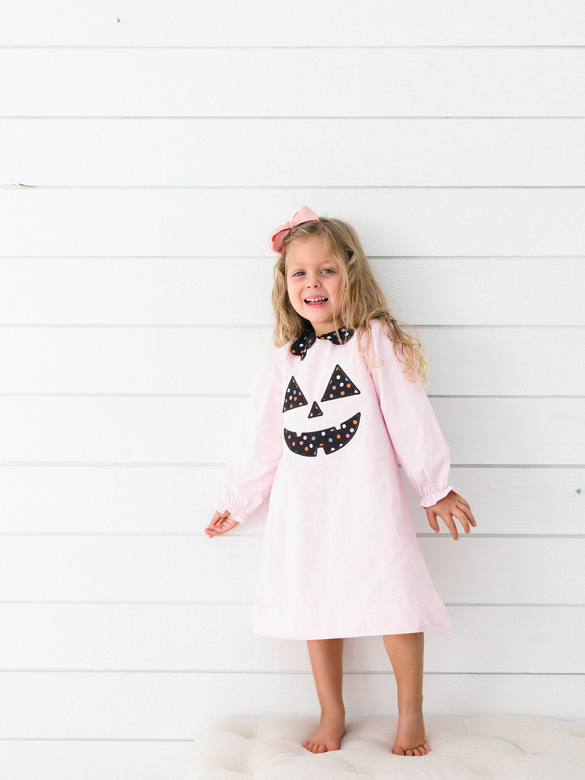  pink long-sleeve dress with a black and white polka-dot jack-o'-lantern face applique