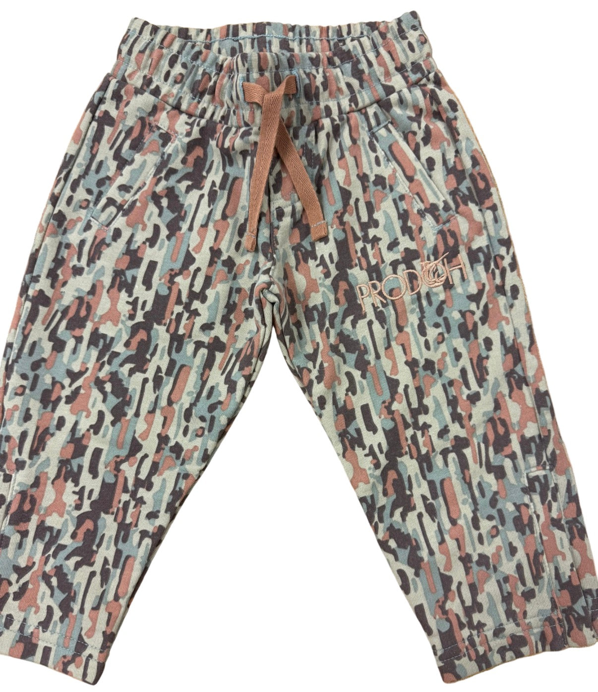 A pair of children's jogger pants featuring an abstract camouflage pattern in beige, brown, black, and muted blue. The pants have an elastic waistband with a brown drawstring and a small embroidered brand logo on the left thigh.