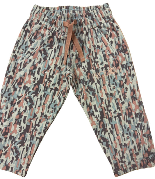 A pair of children's jogger pants featuring an abstract camouflage pattern in beige, brown, black, and muted blue. The pants have an elastic waistband with a brown drawstring and a small embroidered brand logo on the left thigh.