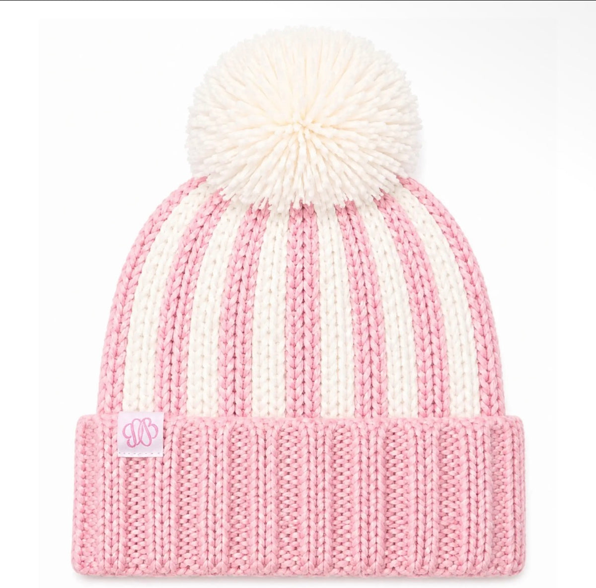 A pink and off-white striped knit beanie with a large white pom-pom on top and a ribbed cuff featuring a small pink monogram patch.