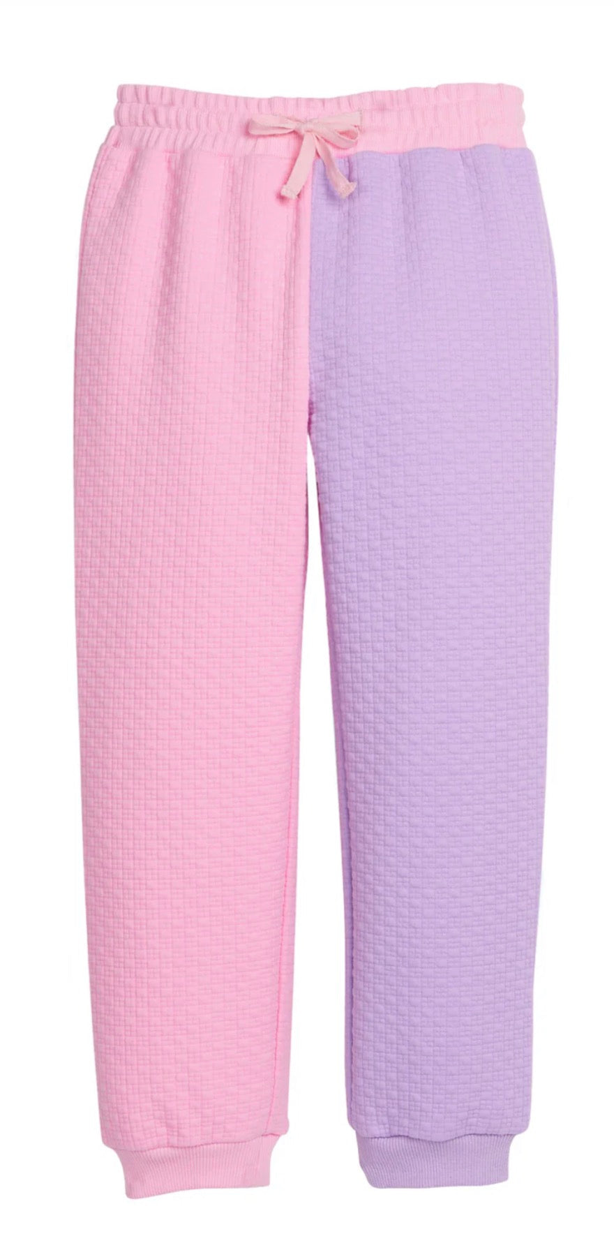 A pair of kids lounge pants with a waffle-knit texture, featuring a split-color design of light pink on the left leg and light purple on the right leg, with a matching drawstring waistband.
