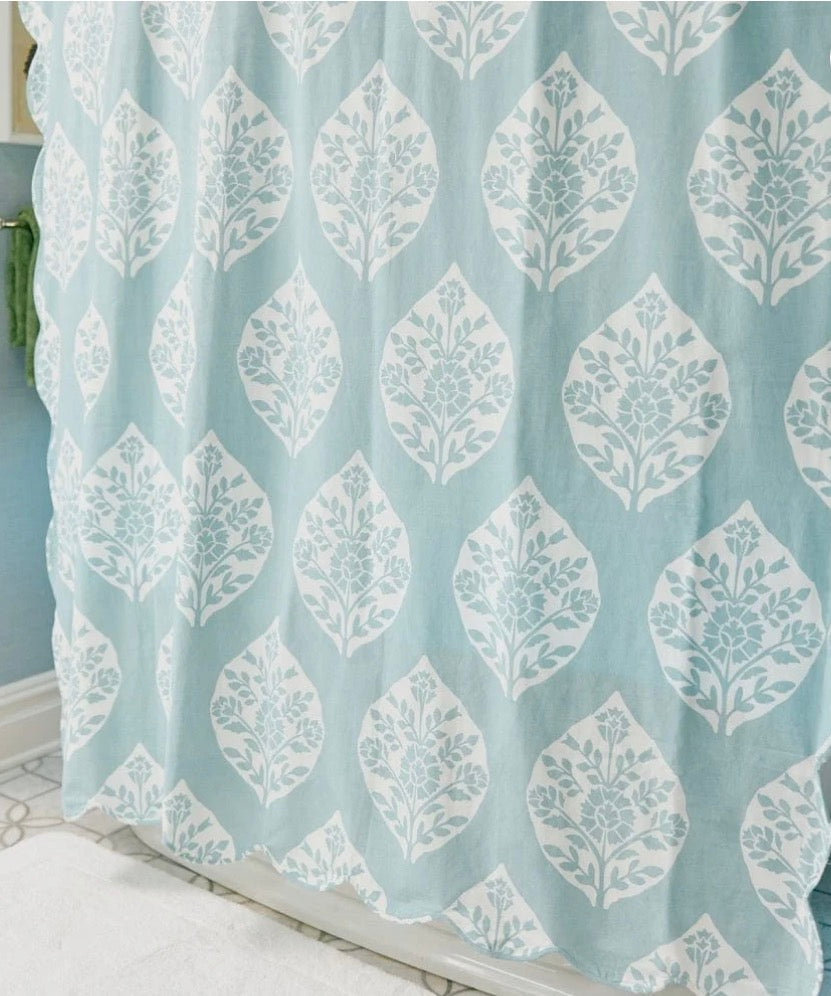A light blue shower curtain with a repeating white damask leaf pattern