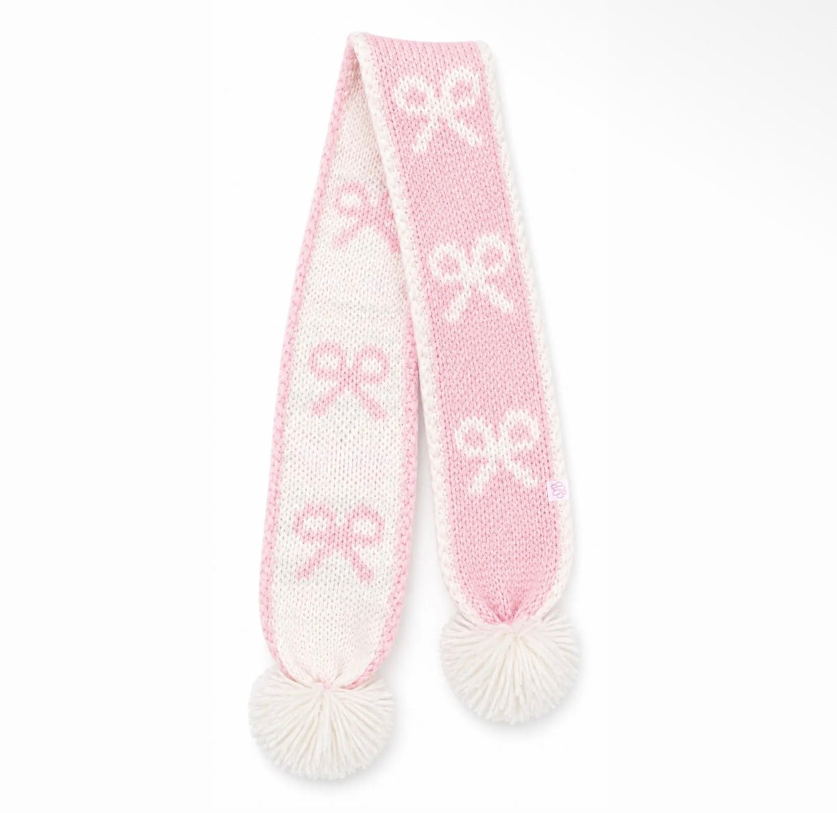 A pink and white knit scarf with white pom-poms on both ends, featuring a repeating bow pattern.