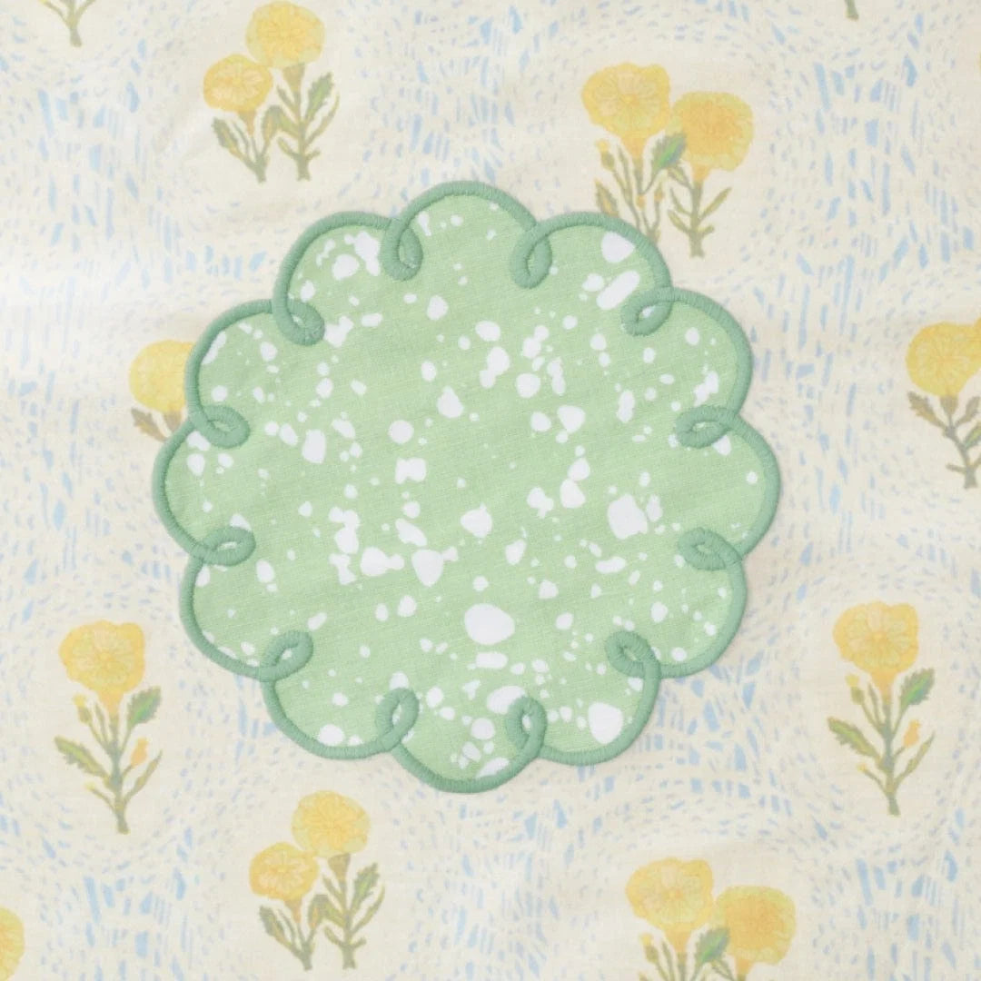 Decorative green cocktail napkins with floral pattern on a textured fabric background