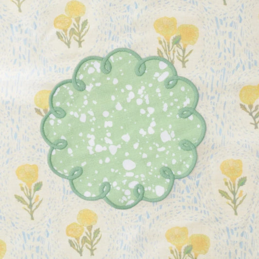 Decorative green cocktail napkins with floral pattern on a textured fabric background