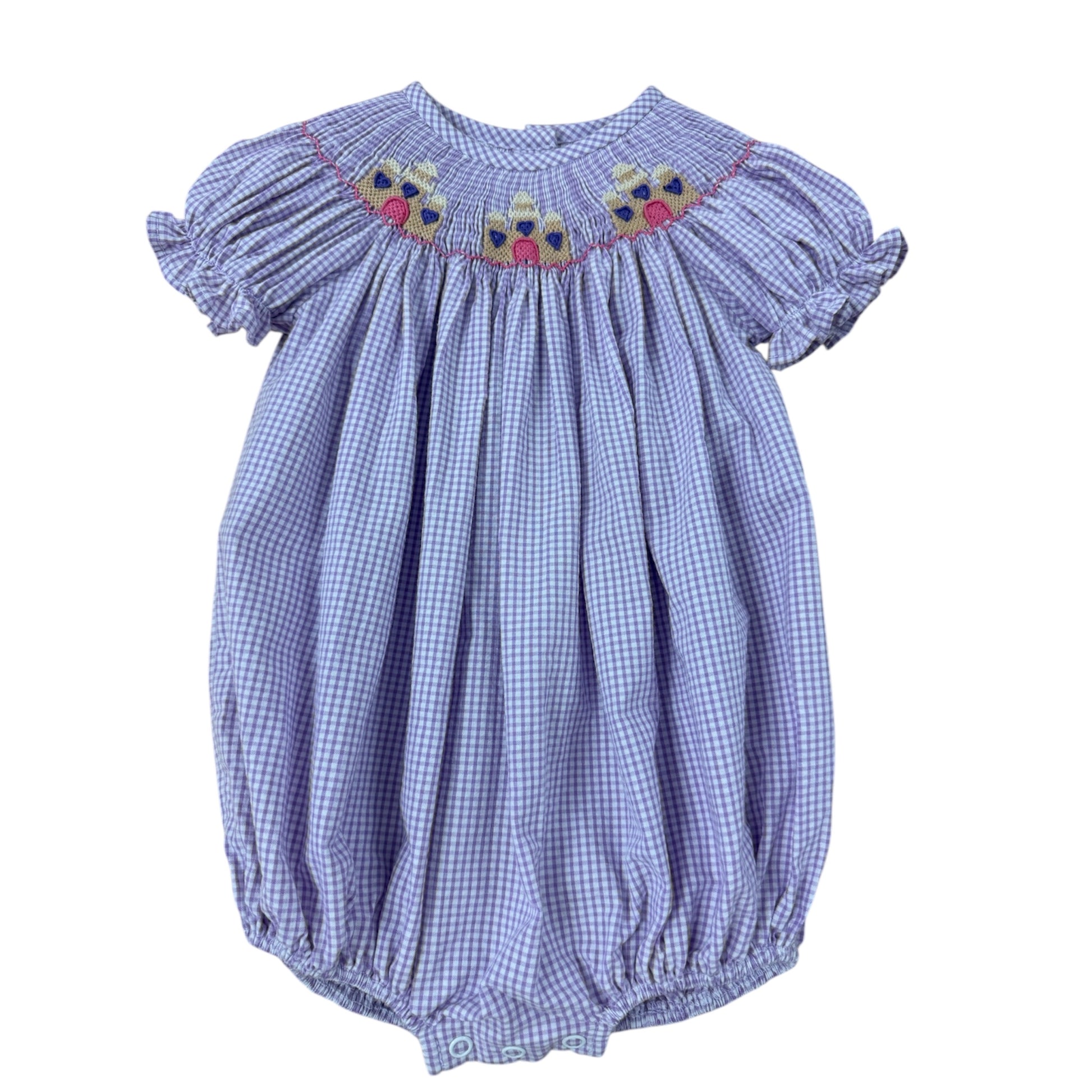 Purple checkered smocked baby romper with sandcastle embroidery on a white background