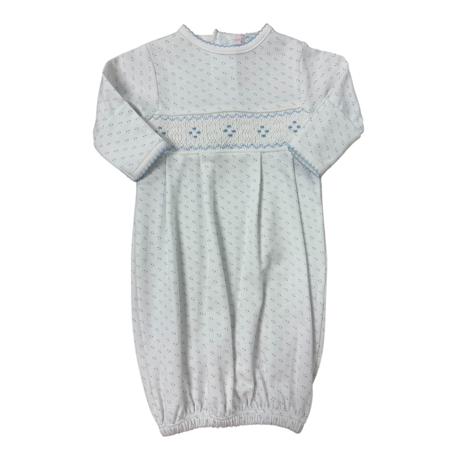 White baby gown with embroidered details on a white background with blue polka dots