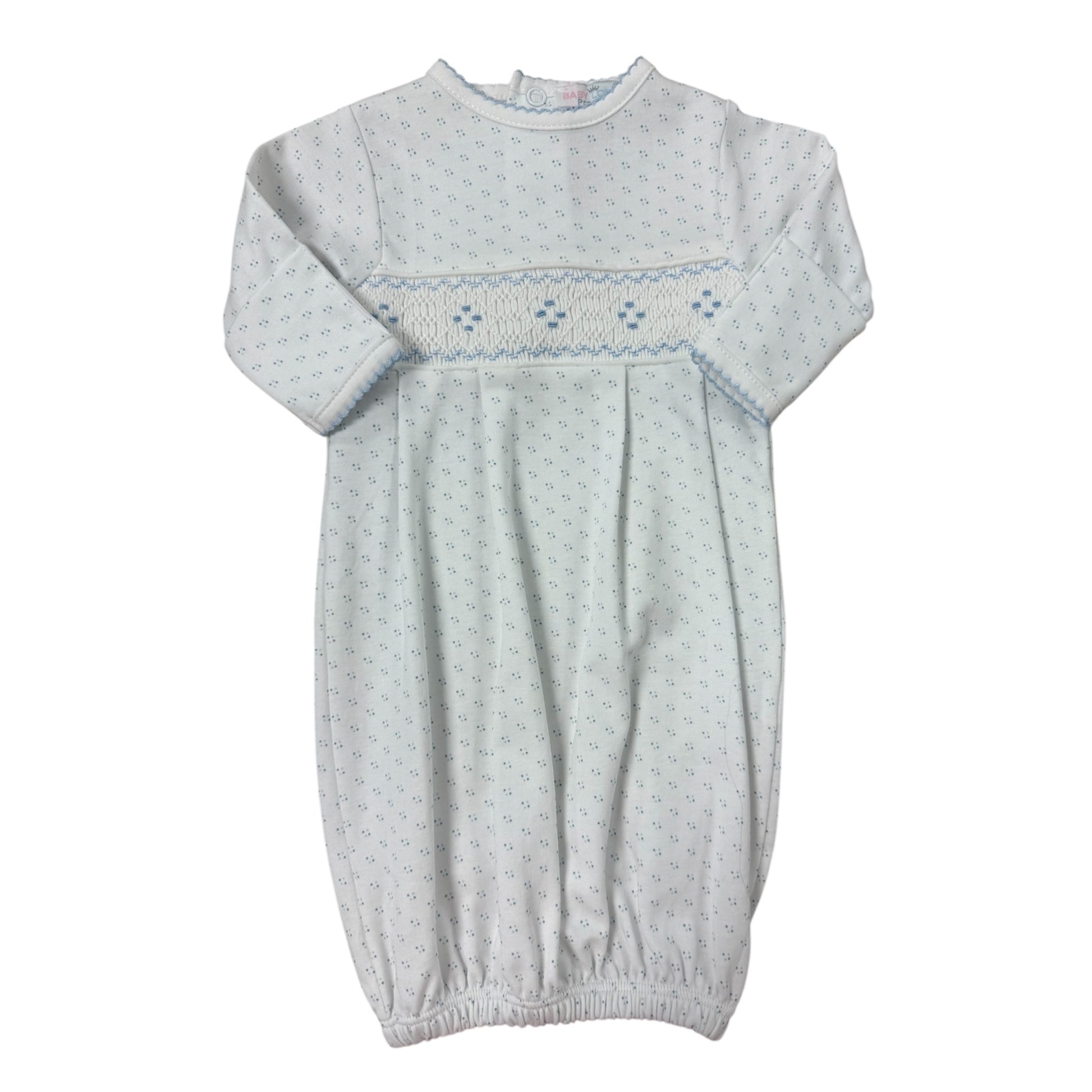 White baby gown with embroidered details on a white background with blue polka dots