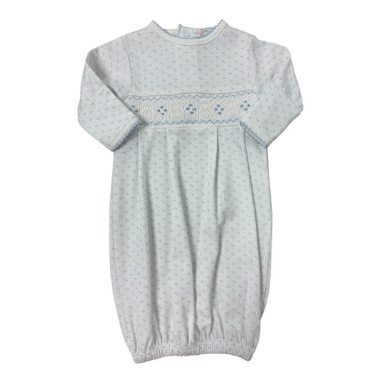 White baby gown with embroidered details on a white background with blue polka dots
