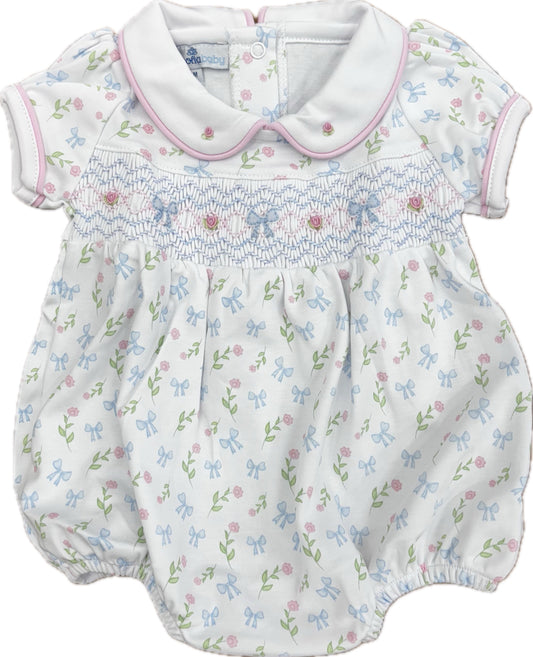 White girl's bubble with blue smocking, pink trim on the collar and short sleeves and an allover flower pattern.