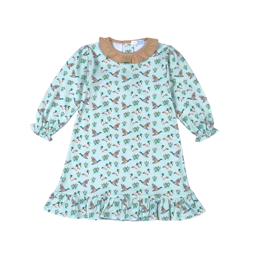 A children's long-sleeve dress with a light mint green background, covered in a pattern of flying ducks and green cacti, featuring a tan ruffled collar and a ruffled hem.