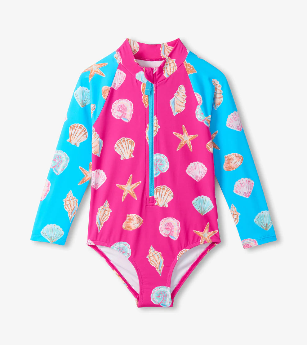 Long sleeve swimsuit with blue sleeves and a pink body and an overall seashell pattern.