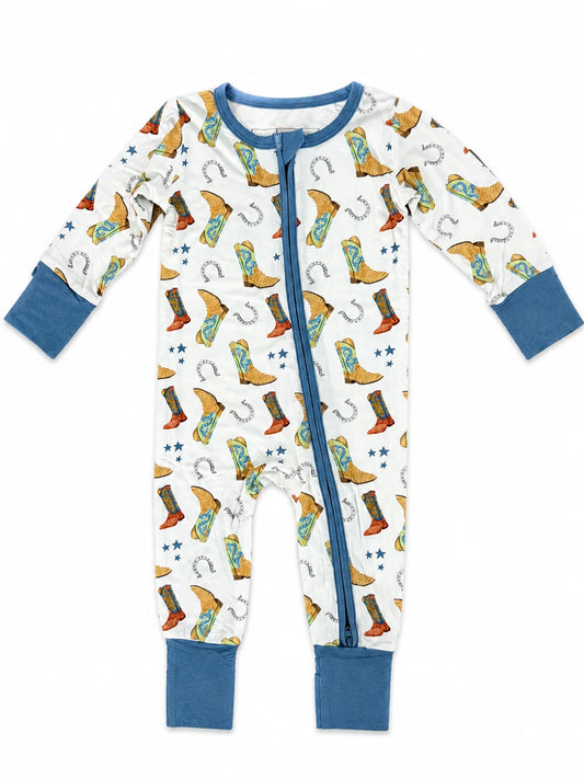 A baby long-sleeve footed sleeper with a white background, featuring a colorful cowboy boot and horseshoe print, blue cuffs, and a blue front zipper.