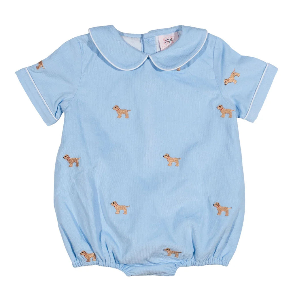 A light blue baby romper with a Peter Pan collar, short sleeves, and an all-over print of small tan dogs, shown flat against a white background.