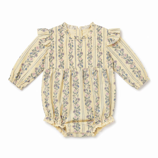 A baby long-sleeve romper in a pale yellowish-beige fabric with vertical stripes and a delicate pink and green floral pattern, featuring ruffled shoulders and a ruffled leg opening.