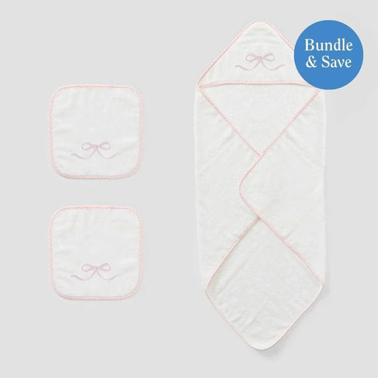 White baby hooded towel with set of two white washclothes all with bow design