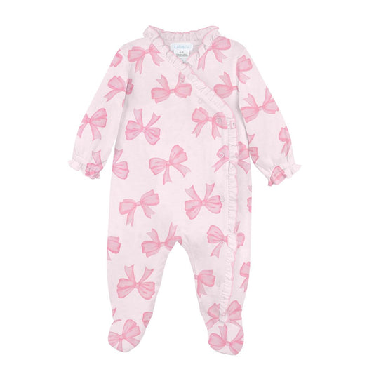 A baby footed sleeper in light pink with a repeating watercolor-style pink bow pattern, featuring ruffle trim along the collar, armholes, and leg cuffs.