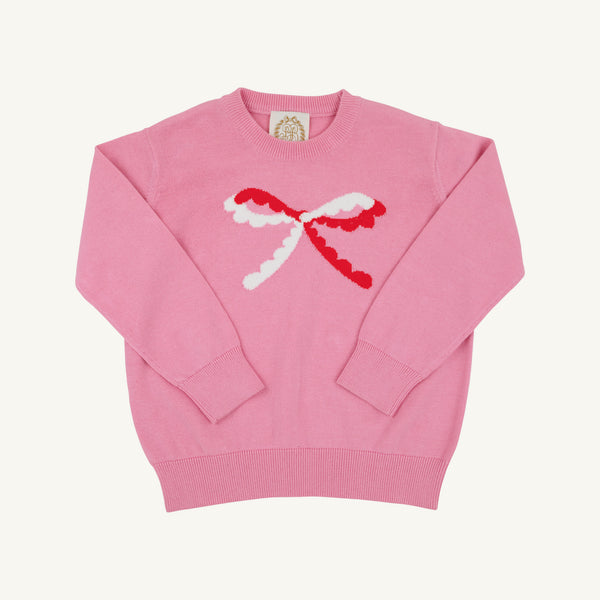 A pink crewneck sweater featuring a large, textured red and white bow motif across the chest, displayed flat against a light cream background.
