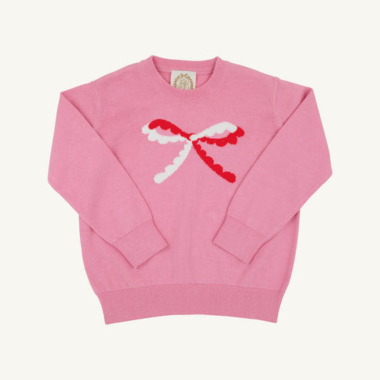 A pink crewneck sweater featuring a large, textured red and white bow motif across the chest, displayed flat against a light cream background.