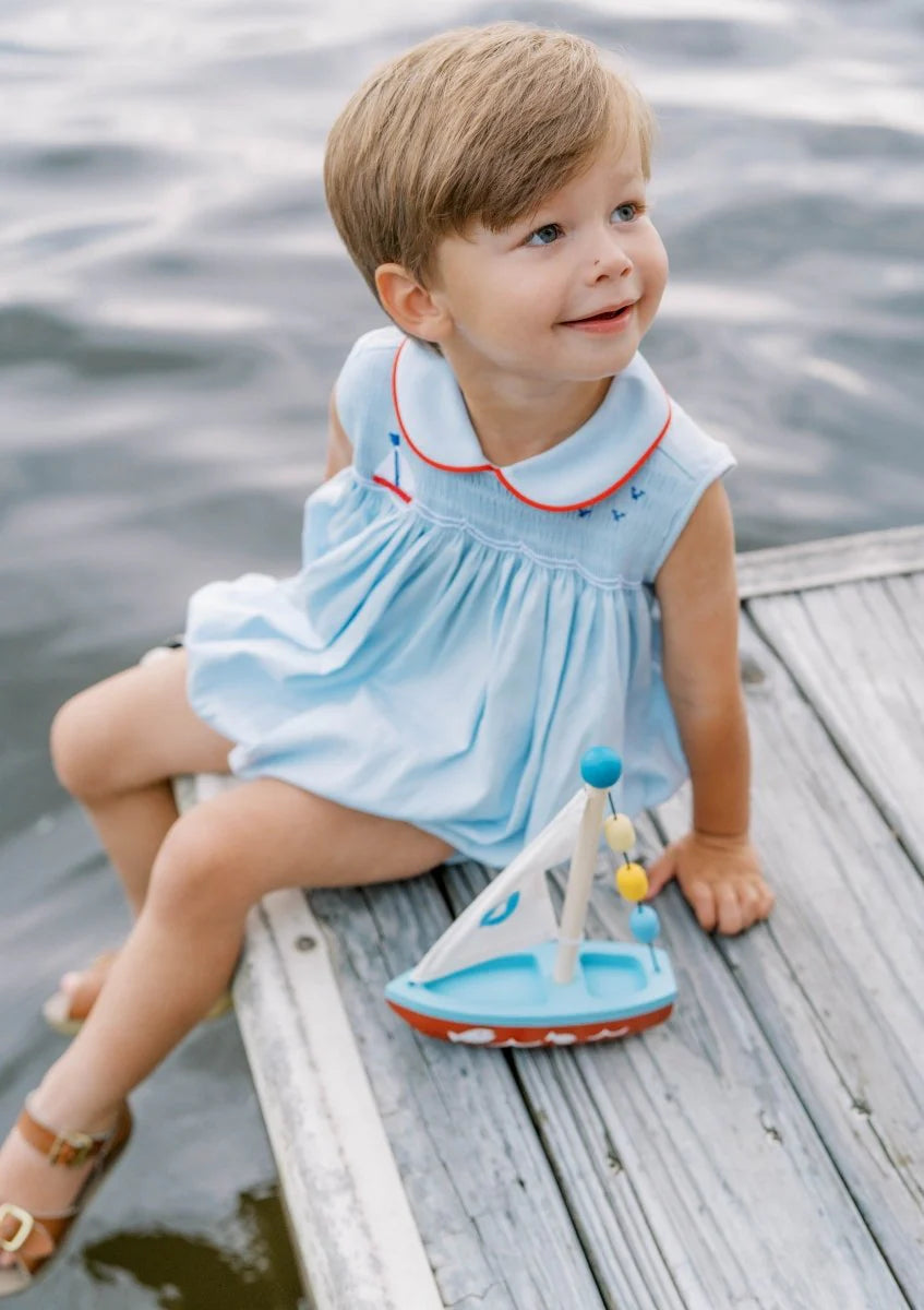 Light blue smocked bubble with sailboat design and red trim