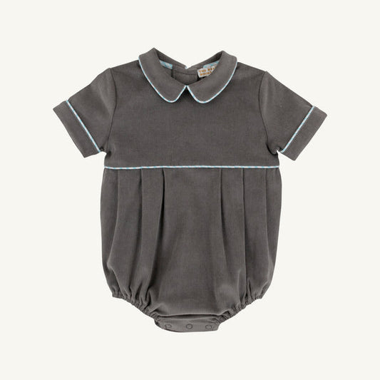 A dark gray baby romper with a pleated bodice, short sleeves, and a Peter Pan collar, featuring light blue piping details on the collar, sleeve cuffs, and a horizontal seam.