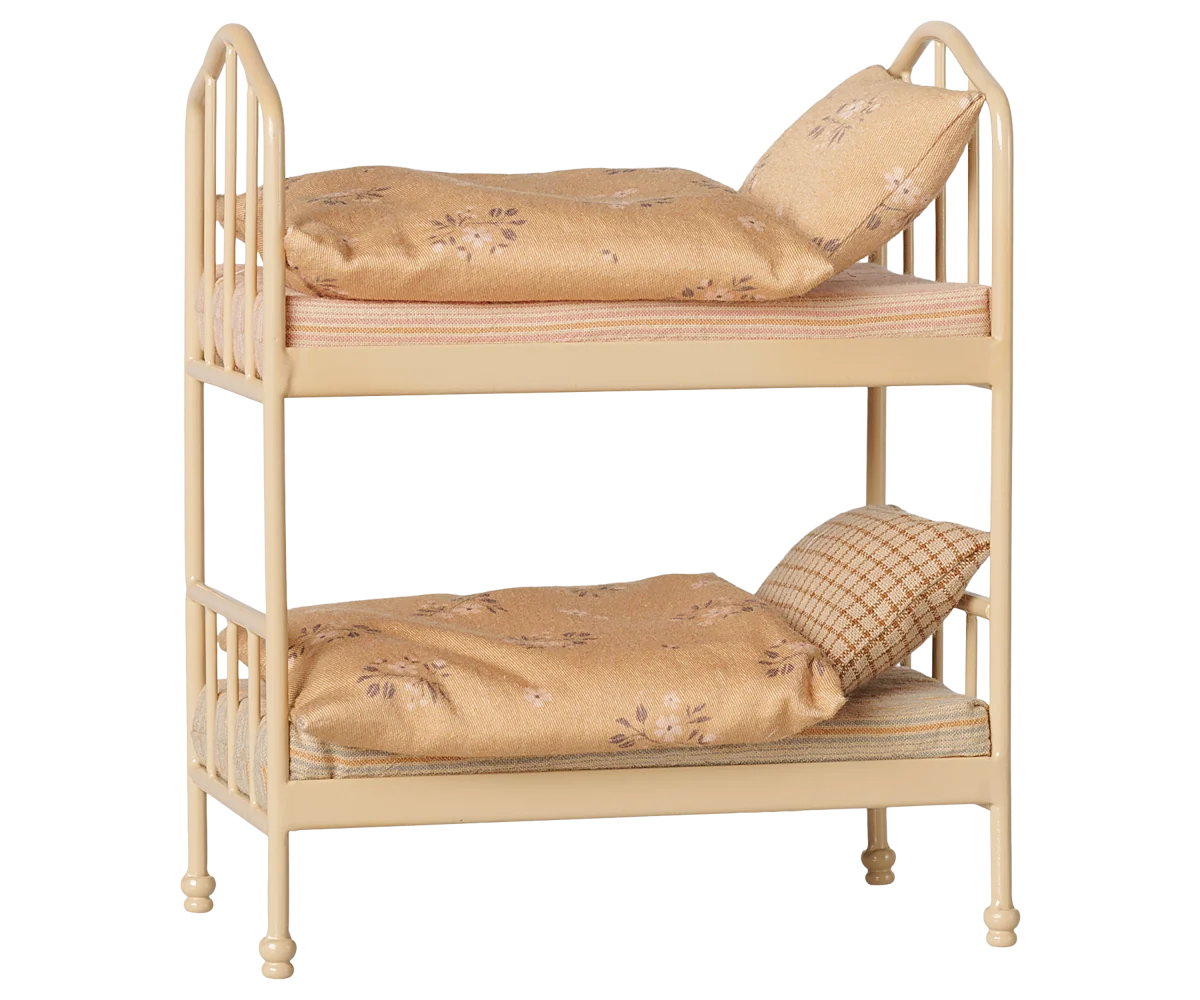 A miniature two-tier wooden bunk bed with a light natural wood finish, styled with beige floral bedding and pillows on a solid white background.