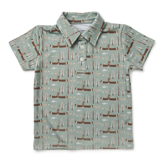A short-sleeve polo shirt for kids, featuring a sage green background with an all-over repeating pattern of brown logs, pine trees, and figures canoeing on the water.
