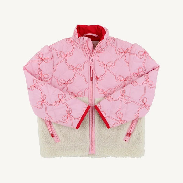 A pink quilted puffer jacket with red bow embroidery and a red inner lining, layered over a cream sherpa fleece jacket, shown flat on a light off-white background.