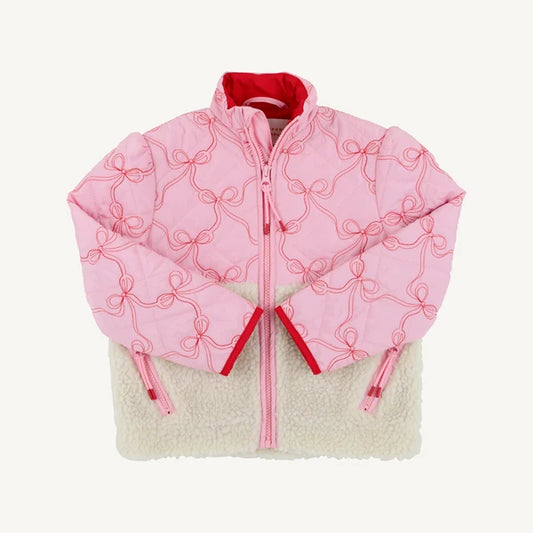 A pink quilted puffer jacket with red bow embroidery and a red inner lining, layered over a cream sherpa fleece jacket, shown flat on a light off-white background.