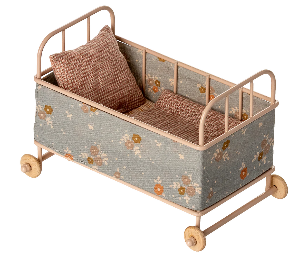 A miniature toy crib or doll's bed with a light wood frame, floral-patterned fabric sides, and two brown checkered pillows, shown on a plain white background.