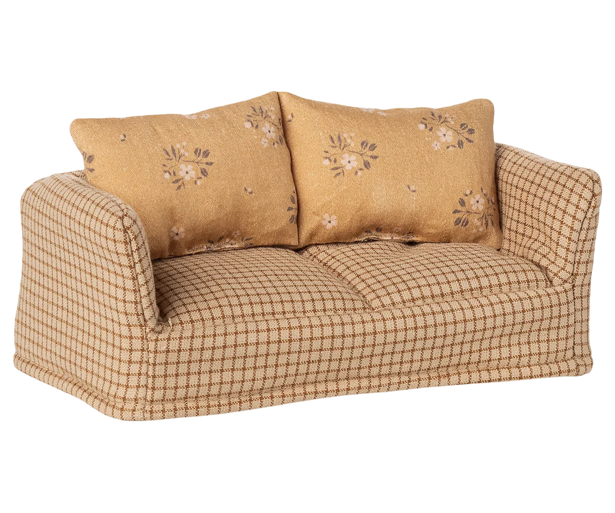 A miniature fabric-covered dollhouse sofa with two matching floral throw pillows, featuring a tan and brown checkered pattern on the seat and arms, and a solid tan background on the pillows.
