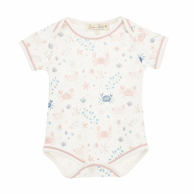 Baby bodysuit with pink crab and shell pattern on a white background