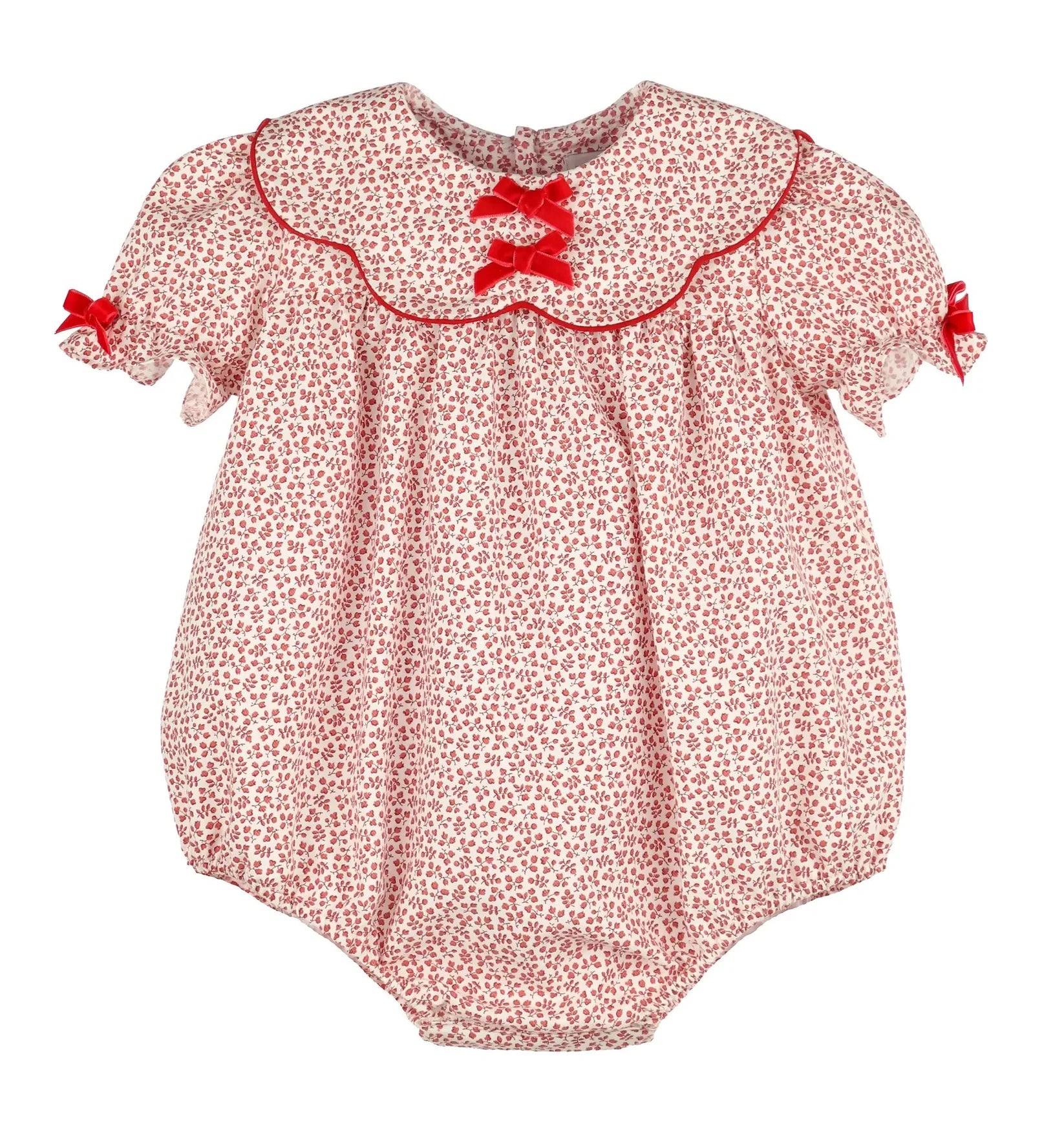 A baby bubble romper in a red and white floral print, featuring a ruffled Peter Pan collar with red trim, red lace-up bows at the neckline, and small red bows on the sleeves.