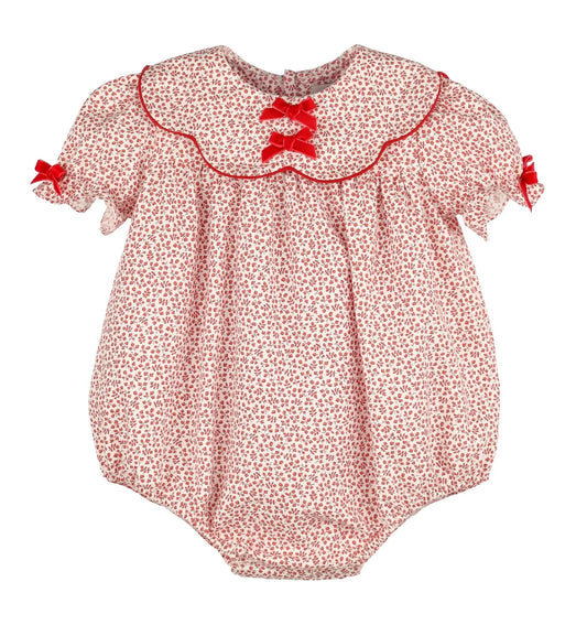 A baby bubble romper in a red and white floral print, featuring a ruffled Peter Pan collar with red trim, red lace-up bows at the neckline, and small red bows on the sleeves.