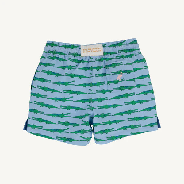 Blue children's swim shorts with green alligator pattern on a light blue background