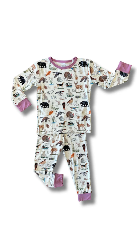 A children's long-sleeve pajama set with matching pants, featuring an all-over woodland animal print on a cream background with pink cuffs and collar.