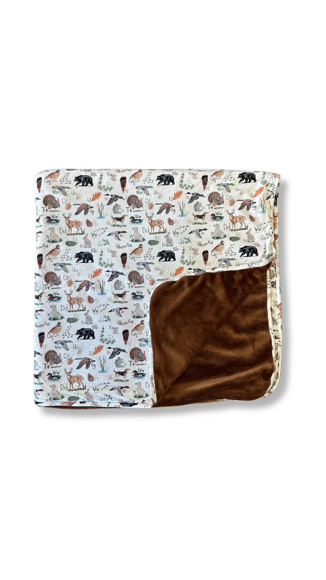 A folded blanket with a woodland animal print on one side and a plush brown suede-like reverse side, shown on a clean white background.