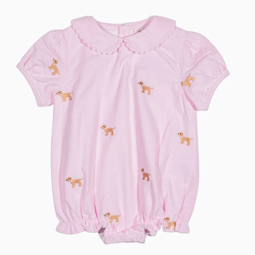 A light pink short-sleeve baby romper with a Peter Pan collar, gathered elastic cuffs, and embroidered dog motifs scattered across the front, shown against a plain white background.