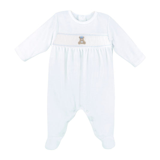 A blue long-sleeve baby footed romper with a smocked chest panel featuring a small embroidered teddy bear.