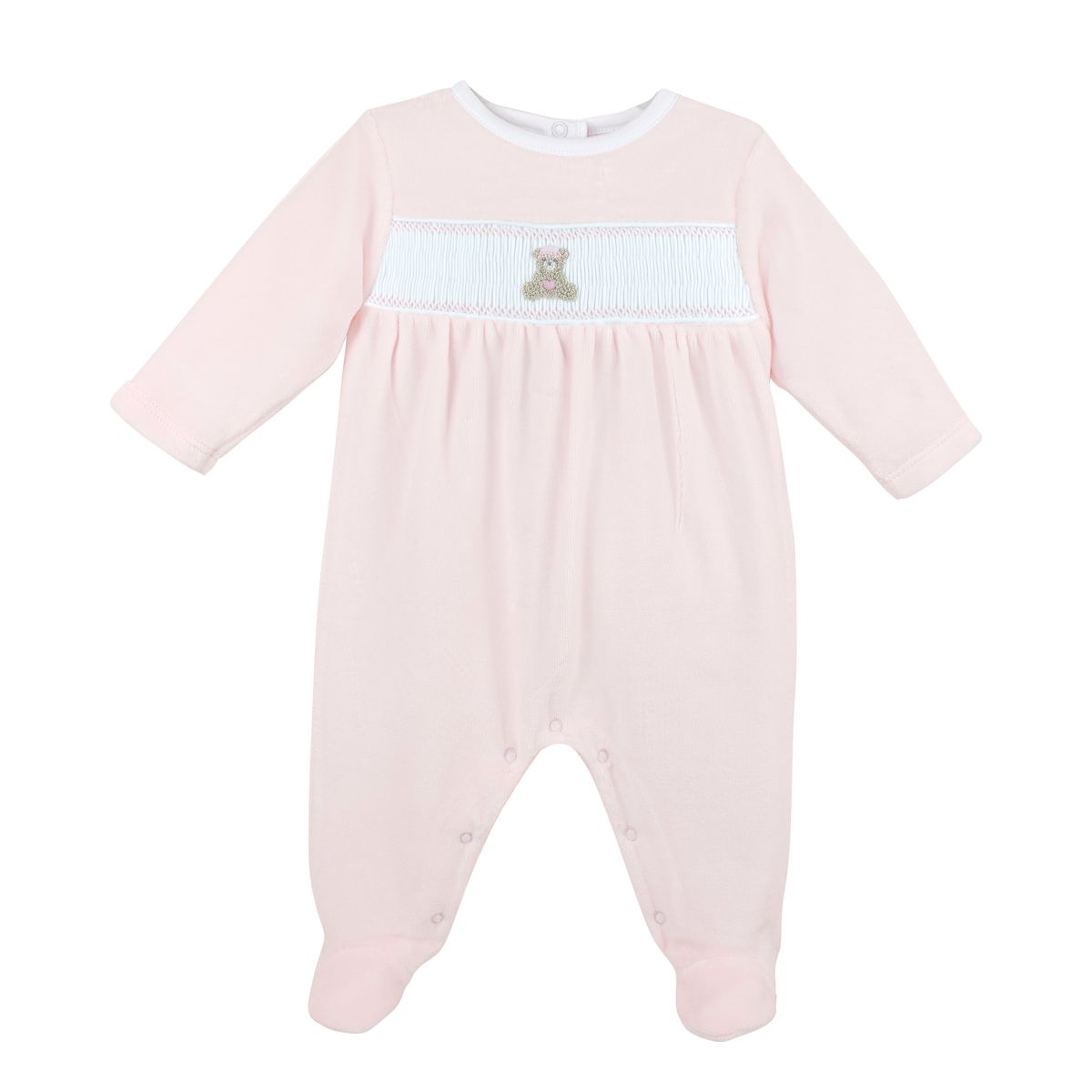 A baby long-sleeve footed romper in light pink, featuring a white smocked chest panel with a small brown teddy bear applique.