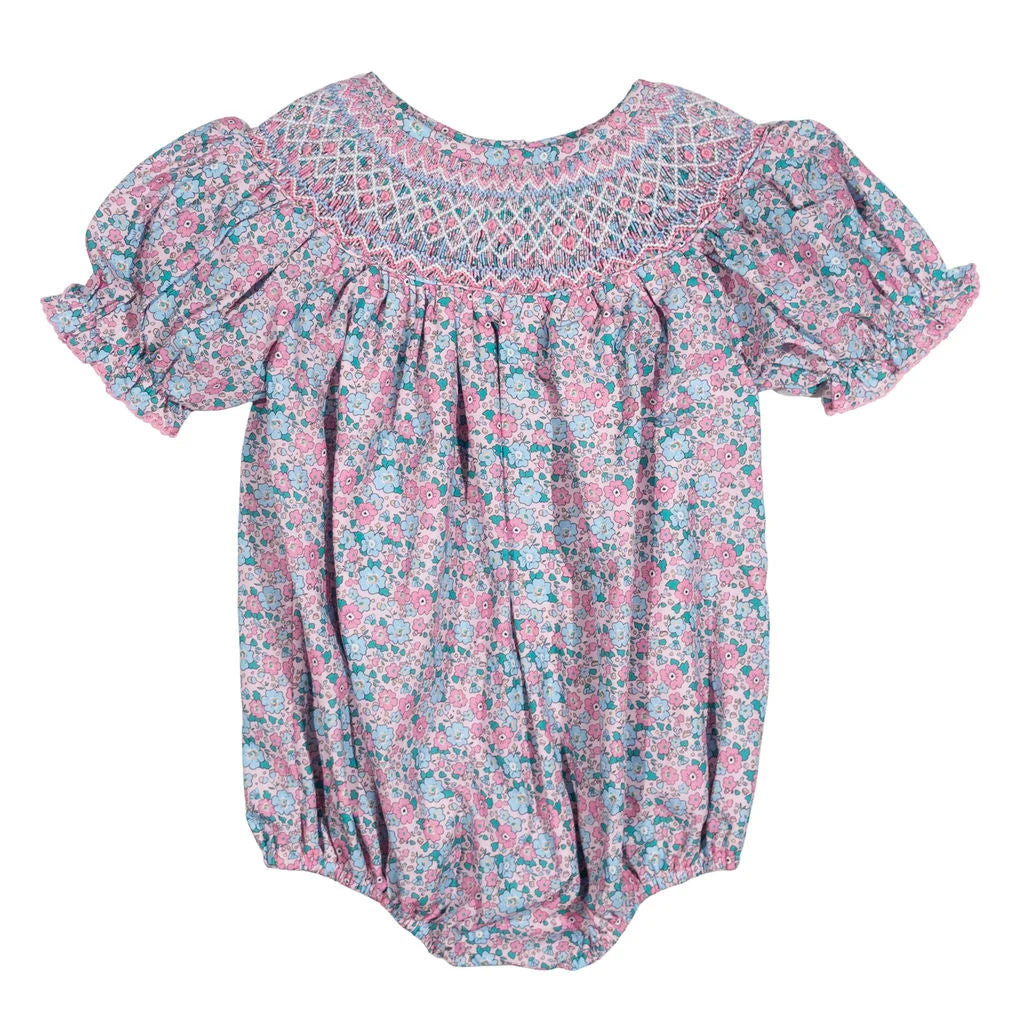 A baby girl's short-sleeve bubble romper in a pink and teal floral print, featuring a smocked yoke with a geometric pattern.
