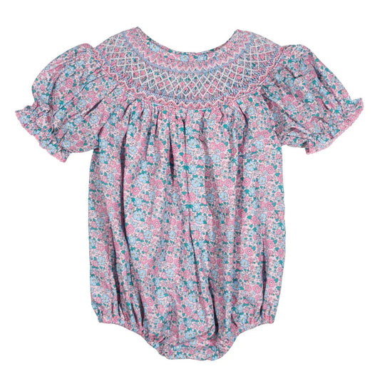 A baby girl's short-sleeve bubble romper in a pink and teal floral print, featuring a smocked yoke with a geometric pattern.