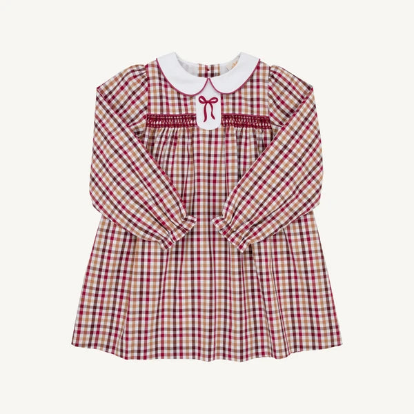 A long-sleeve baby dress with a red and beige gingham pattern, featuring a white Peter Pan collar, smocked chest detailing with a red bow, and elasticized cuffs.