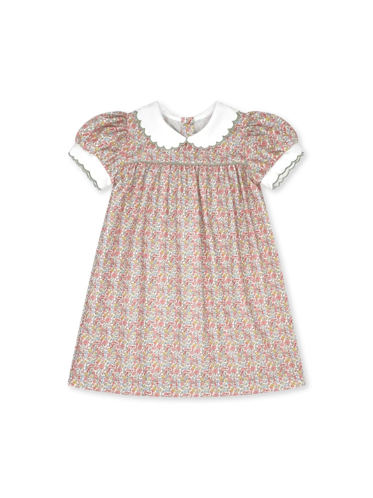 A toddler girl's short-sleeve dress with a dense multicolor floral print on a light beige background, featuring a contrasting white Peter Pan collar and white sleeve cuffs with delicate green trim.